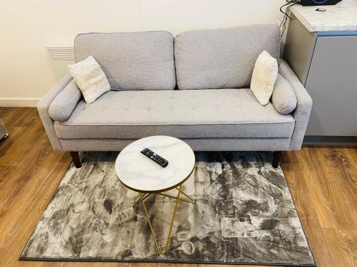a couch with a remote control on a table at Buckinghamshire Elegant Studio in Buckinghamshire