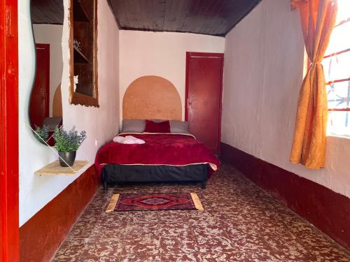 a bedroom with a bed with a red comforter at Habitación Amapola in Girardota