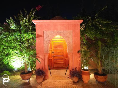 a wooden door in a garden with potted plants at Villa Taj Sofia & Spa in Marrakech