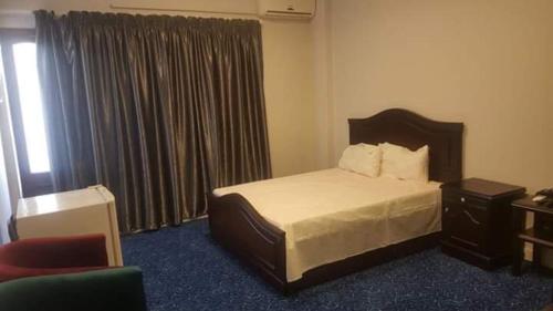 een slaapkamer met een bed, een stoel en een raam bij فندق الامرات ٣٣ النيل in ‘Izbat al Jirabī