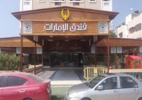 um edifício com dois carros estacionados em frente em فندق الامرات ٣٣ النيل em ‘Izbat al Jirabī