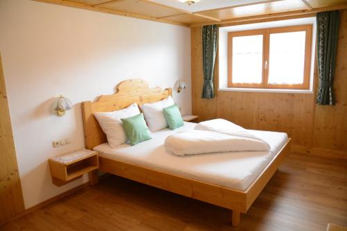 Schlafzimmer mit einem Bett mit einem Kopfteil aus Holz und einem Fenster in der Unterkunft Appartements Alpenblick in Kirchberg in Tirol