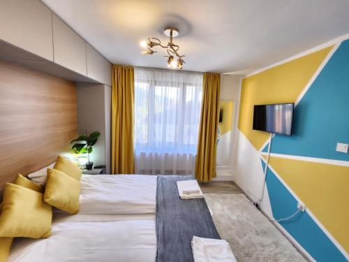 una habitación de hotel con una cama grande con paredes amarillas y azules en Bulgarane House en Govedartsi