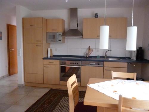 a kitchen with wooden cabinets and a table with a dining room at Haus am Stellensee in Sternenfels