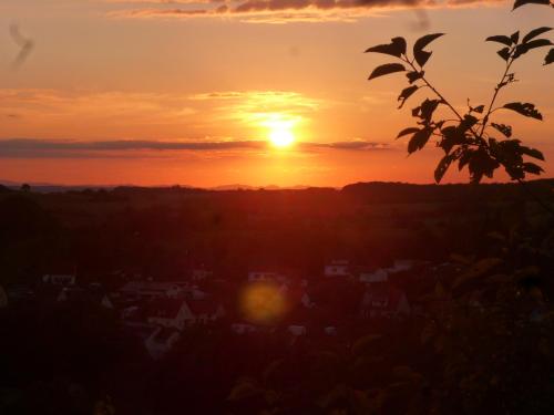 a sunset with the sun setting over a city at Haus am Stellensee in Sternenfels