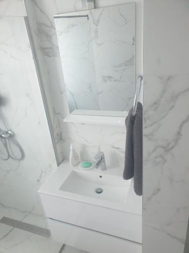 a white bathroom with a sink and a mirror at Apartament Resort in Constanţa