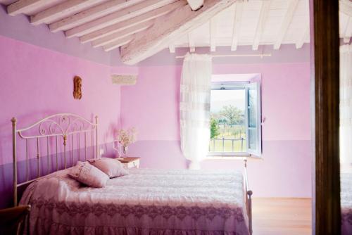 Tenuta Le Tre Virtù في سكاربيرا: غرفة نوم وردية مع سرير ونافذة