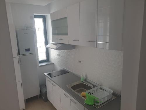 a kitchen with white cabinets and a sink and a window at Apartament Resort in Constanţa
