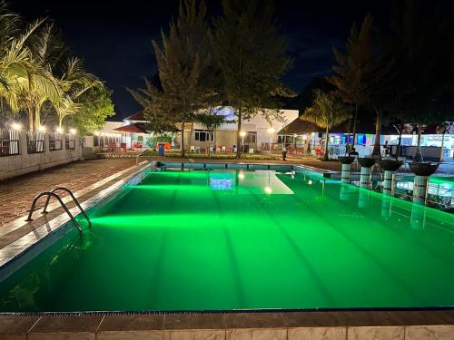 a swimming pool with green illumination at night at Kakiri Gardens and Hotel in Wakiso