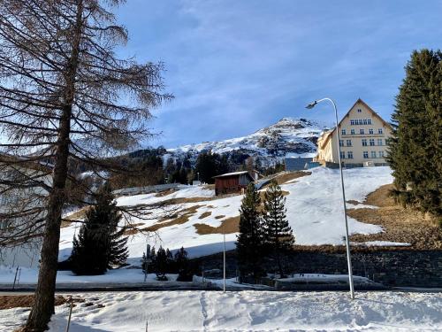 um edifício sobre uma colina coberta de neve com uma montanha em La Suite Swiss Alps em Davos