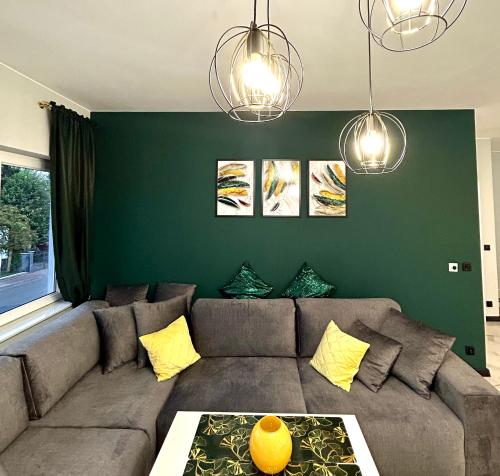 a living room with a couch and a green wall at Premium Exclusive Suite in Nowy Dwór Mazowiecki