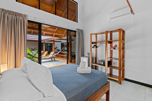 a bedroom with a white bed and a balcony at Villa Ave del Paraíso in Playa Avellana