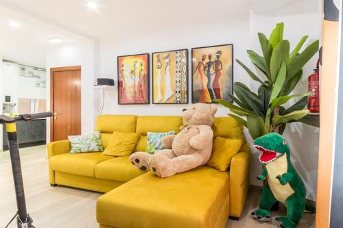 a yellow couch with a teddy bear on it in a living room at LUJO: Parking, Proyector, Maquinita y Patinetes in Oviedo