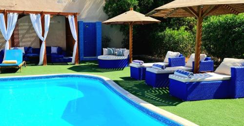una piscina con sillas azules y sombrillas junto a una piscina en Luxury Royal Blue Family Villa 8pers private pool, en Hurghada