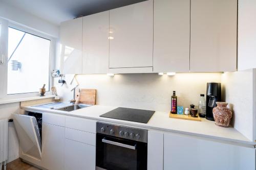 kuchnia z białymi szafkami, zlewem i kuchenką w obiekcie Luxurious maisonette apartment at the heart of Vienna w Wiedniu