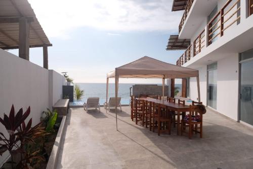 un patio con mesa, sillas y el océano en Las Fragatas Casa Hotel en Canoas de Punta Sal