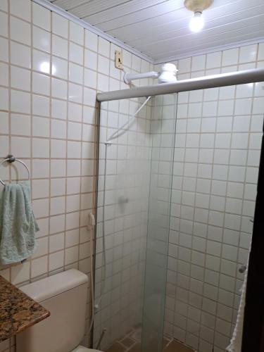 a bathroom with a toilet and a glass shower door at Vilage Taipan 02 - Praia Stella Maris in Salvador