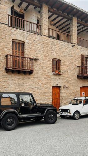 a black jeep and a white car parked in front of a building at Casa Boixareu in La Pobla de Segur