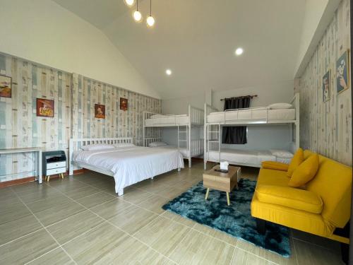 um quarto com 2 beliches e um sofá amarelo em บ้านไร่โฮมเทล ณ ปากช่อง em Ban Nong Takhain