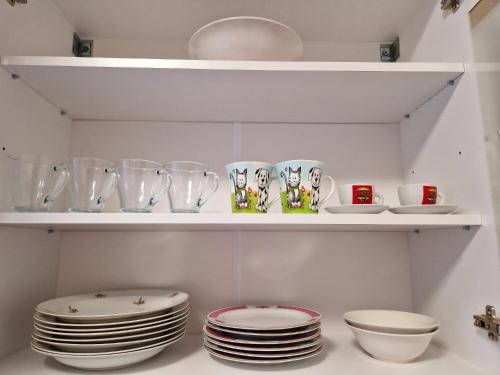 a shelf with plates and cups and dishes on it at ORI Passion Apart. Malul Mureșului in Arad