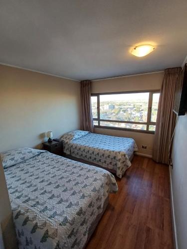 a hotel room with two beds and a window at Departamento Central en Calama in Calama