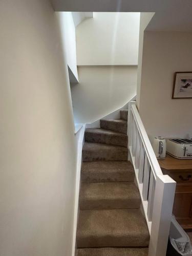 a staircase in a house with white walls and carpet at The Barn in South Witham