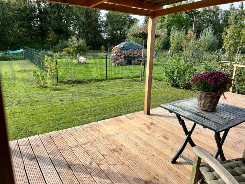 a wooden deck with a table with a basket of flowers at Vrijstaand chalet met veel buitenruimte en veranda in Zuid-Scharwoude