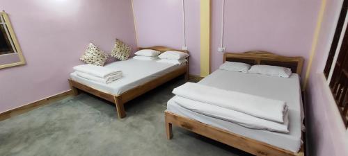 two beds in a small room with two chairs at Sai Saraswati Homestay in Kalimpong