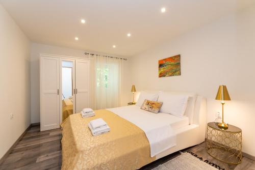 a white bedroom with a large bed and a table at LA MARLENA in Benkovac
