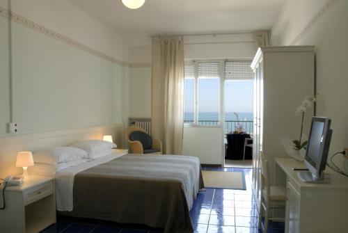 1 dormitorio con cama, TV y balcón en Hotel Caravelle, en Cattolica
