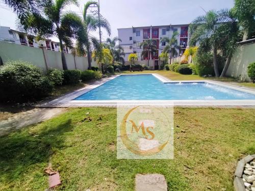 una piscina en un patio con un cartel en el césped en Imus Cavite Stayction - 1 Bedroom Condo Unit - Urban Deca Homes - Olive Bldg en Imus