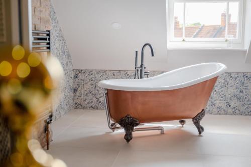a bath tub in a bathroom with a window at The Sheep and Penguin in Wells