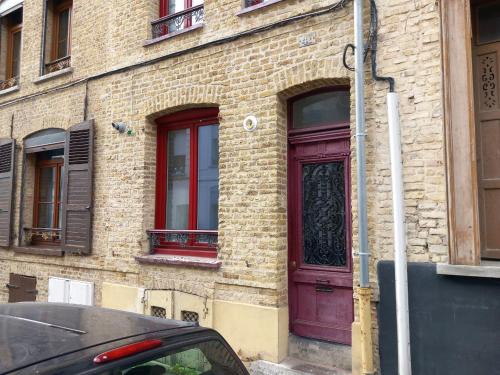 un bâtiment en briques avec une porte violette dans une rue dans l'établissement Appart'Hotel Saint-Omer, à Saint-Omer