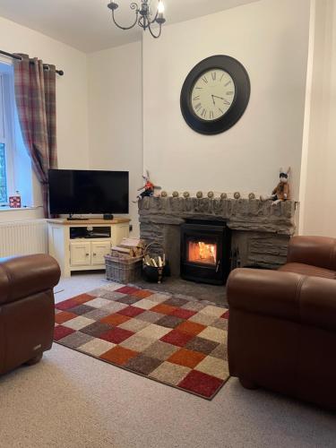 a living room with a fireplace and a clock on the wall at Quarry Cottage near Hawes, Yorkshire Dales, Pet free in Hawes