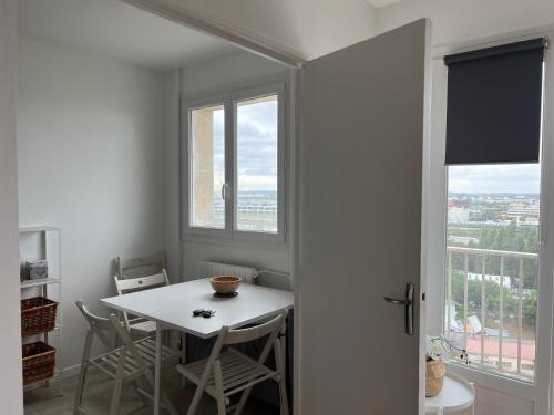 een witte tafel en stoelen in een kamer met een raam bij Studio Pantin - 10min Paris/20min Stade de France in Pantin