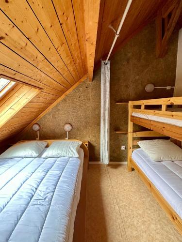 two beds in a room with a wooden ceiling at LE LAC BLEU - Duplex au pied des remontées mécaniques in Cauterets