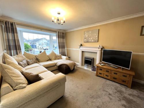a living room with a couch and a flat screen tv at Tranquil 3-bedroom bungalow in Kirkhamgate