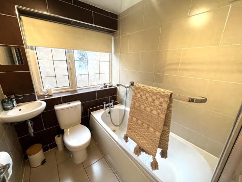 a bathroom with a toilet and a bath tub and a sink at Tranquil 3-bedroom bungalow 