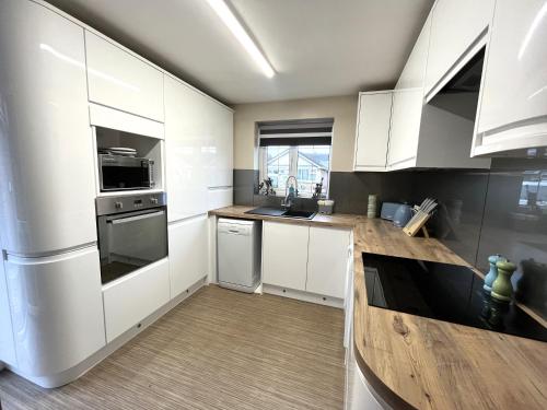 a kitchen with white cabinets and a wooden counter top at Tranquil 3-bedroom bungalow in Kirkhamgate