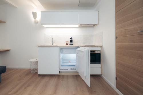 Una pequeña cocina con gabinetes blancos y un fregadero. en Le petit bellifontain, en Fontainebleau