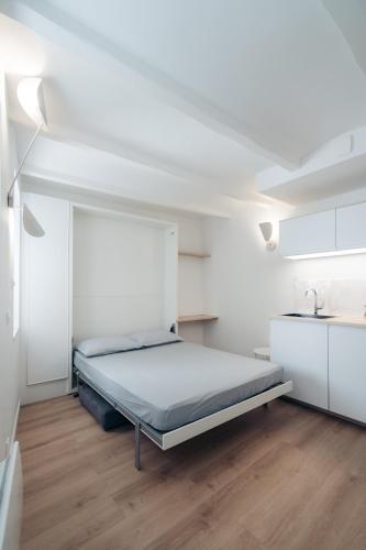 une chambre blanche avec un lit et un parquet dans l'établissement Le petit bellifontain, à Fontainebleau