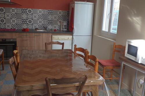 une cuisine avec une table, des chaises et un réfrigérateur dans l'établissement la maison du bonheur, à Saint-Laurent-de-la-Salanque