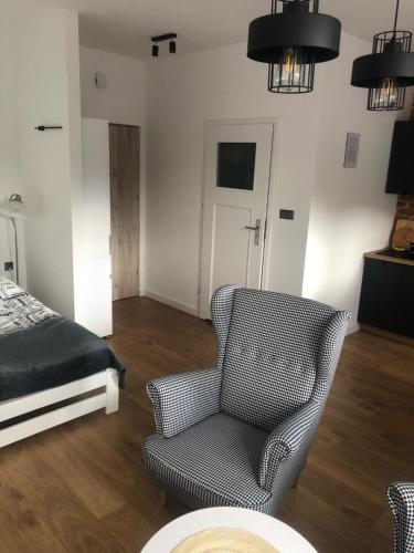 a living room with a chair and a bed at Apartament BROWARNY II in Ostrów Wielkopolski
