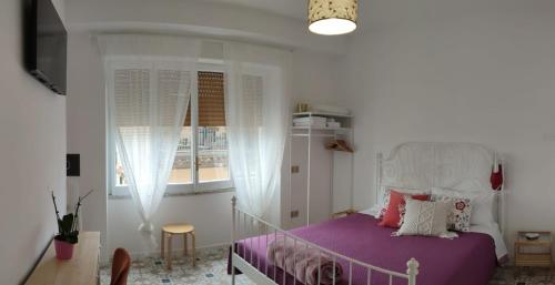 a bedroom with a bed with purple sheets and a window at Edahouse in Salerno