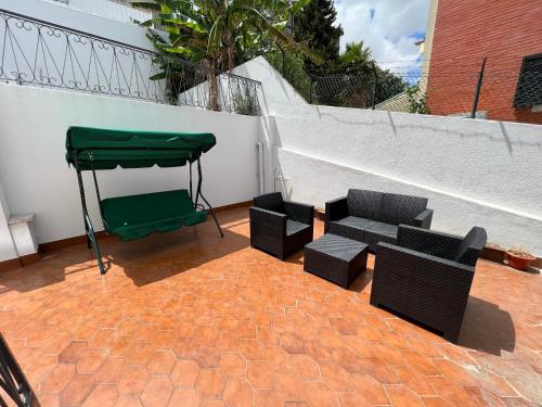 奧埃拉什的住宿－Oeiras Beach guest house，天井配有两把椅子和绿色天篷