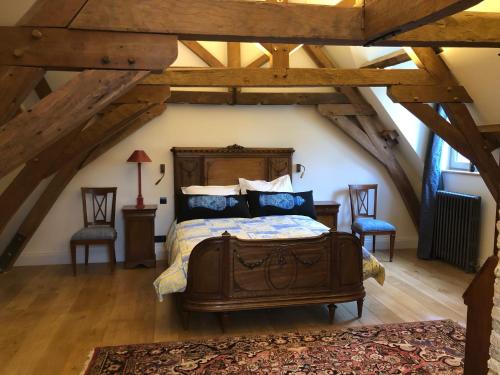 a bedroom with a bed and two chairs in a attic at CLOS DU BAILLI in Saint-Omer