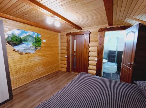 Habitación en una cabaña de madera con cama y aseo en Villa Zgarda1 en Mykulychyn