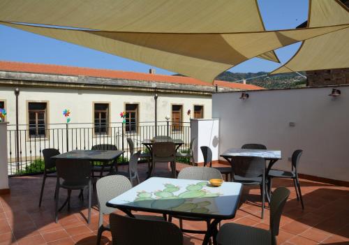 un patio con mesas y sillas bajo una sombrilla grande en ficodindia Suite & Apartments, en Santo Stefano di Camastra