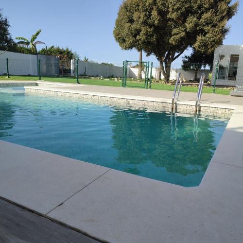 a swimming pool with blue water in a park at Paraíso del bienestar in Cádiz