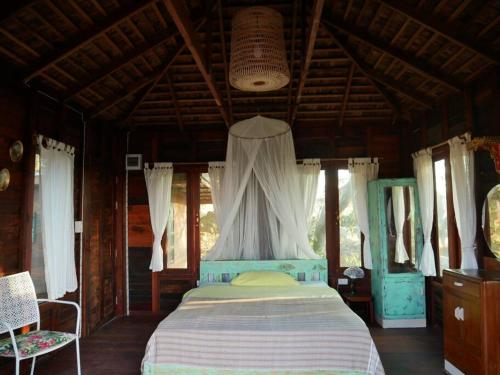 Un dormitorio con una cama en una habitación con ventanas. en Villa Noina Farmstay Thai house style, en Ban Nong Takhain